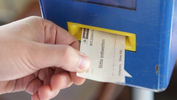 Eine Hand entwertet eine Fahrkarte der Wiener Linien an einem Automaten.