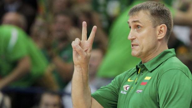 Ein Basketballtrainer in grüner Kleidung zeigt mit der Hand die Zahl Drei.