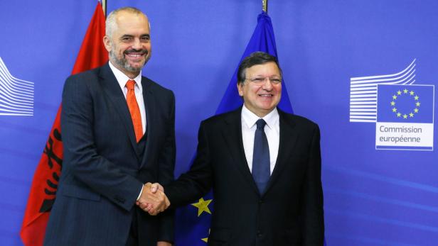 Edi Rama und ein weiterer Mann schütteln sich vor Flaggen der EU und Albaniens die Hände.