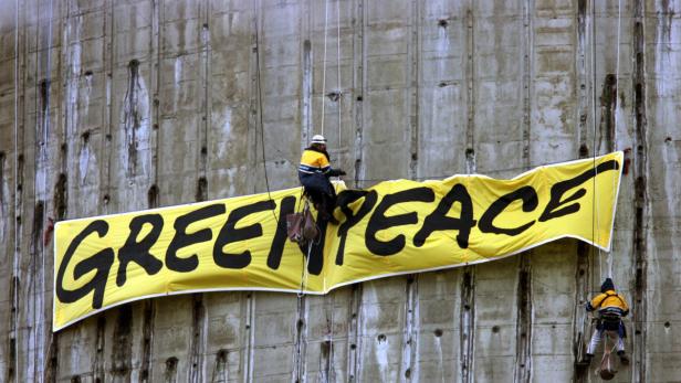 Aktivisten der Umweltorganisation Greenpeace entfalten an einem Kraftwerk ein Banner.