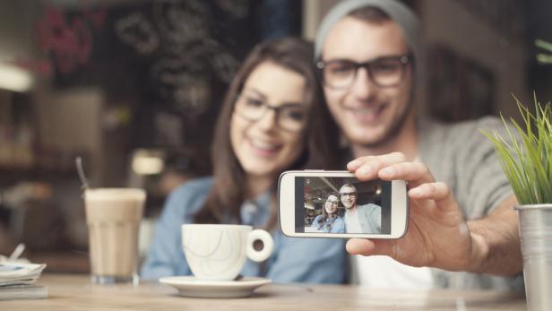 Ein Paar macht ein Selfie in einem Café.