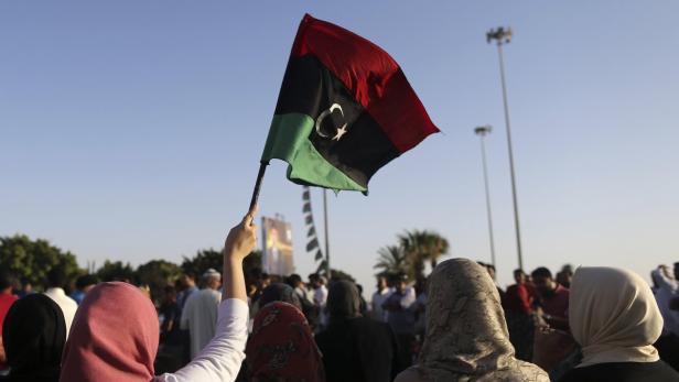 Eine Person hält eine libysche Flagge in einer Menschenmenge.