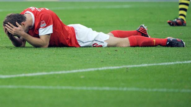 Ein Fußballspieler liegt enttäuscht auf dem Rasen.