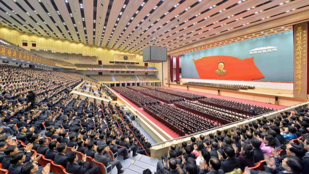 Eine riesige Menschenmenge in einer Halle applaudiert vor einem Porträt von Kim Il-sung.