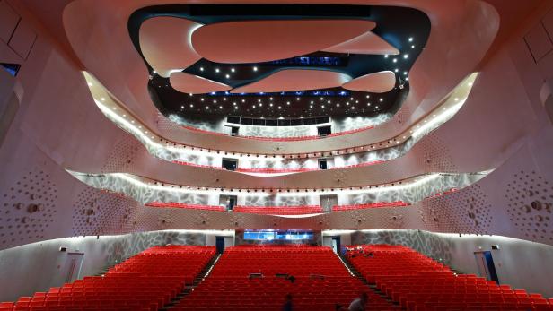 Innenansicht eines Theatersaals mit roten Sitzen und geschwungenen Balkonen.