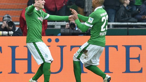 Zwei Fußballspieler von Werder Bremen feiern gemeinsam auf dem Spielfeld.