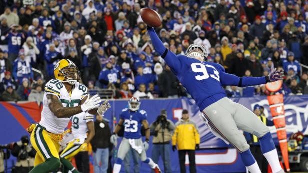 Ein Footballspieler der Giants fängt einen Pass vor einem Spieler der Packers.