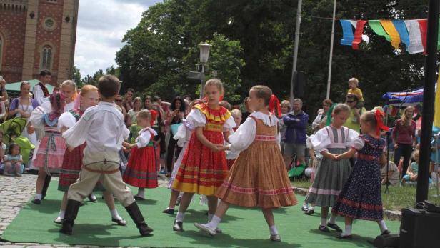 Eine Gruppe Kinder tanzt in traditionellen Trachten auf einer Bühne.