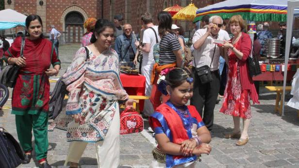 Eine junge Frau in traditioneller Kleidung steht auf einem belebten Platz.