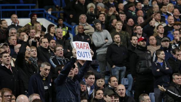 Ein Mann hält ein Schild mit der Aufschrift „Rafa Out!“ in einer Menschenmenge.