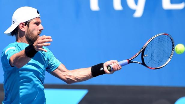 Ein Tennisspieler schlägt einen gelben Tennisball mit seinem Schläger.