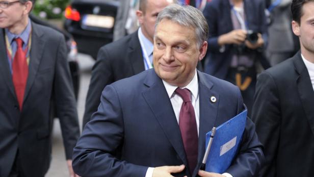 Viktor Orbán bei einer Veranstaltung mit einer blauen Mappe in der Hand.