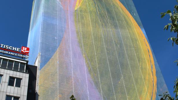 Ein Hochhaus mit einem großen, farbenfrohen Kunstwerk an der Fassade.