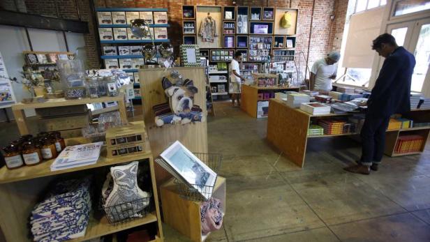 Patrons are pictured as they browse an Urban Outfi In einem Ladenlokal stöbern Kunden in Regalen voller Bücher und anderer Waren.
