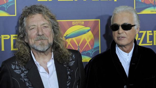 Robert Plant und Jimmy Page von Led Zeppelin posieren vor einem Bandplakat.