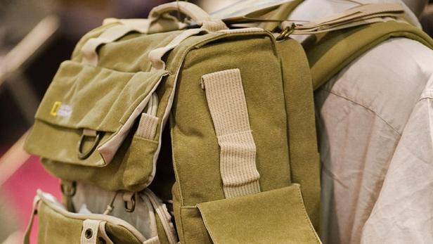 Eine olivgrüne National Geographic Kameratasche wird von einer Person getragen.