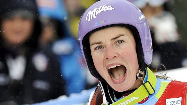Eine Skirennläuferin schreit mit offenem Mund, während sie einen lila Helm trägt.