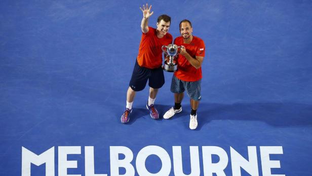 Zwei Tennisspieler posieren mit einer Trophäe auf einem Platz in Melbourne.