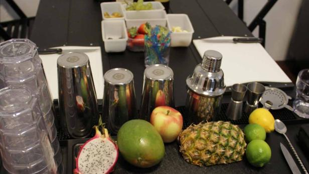 Zutaten und Barwerkzeug für die Zubereitung von Cocktails auf einem Tisch.