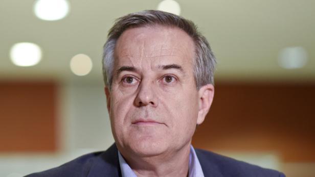 Porträt eines Mannes mit grau meliertem Haar und einem blauen Hemd.