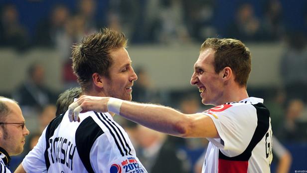 Zwei Handballspieler umarmen sich auf dem Spielfeld.