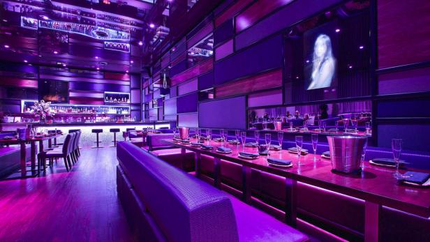 Ein elegant eingerichtetes Restaurant mit lila Beleuchtung und gedeckten Tischen.