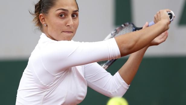 Eine Tennisspielerin schlägt einen gelben Tennisball.