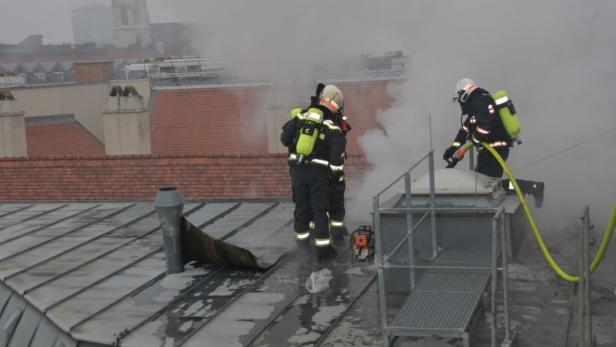 Feuerwehrleute arbeiten auf einem Dach inmitten von Rauch.