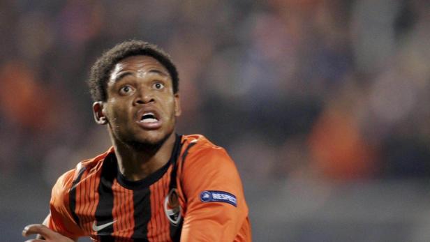 Ein Fußballspieler in einem orange-schwarz gestreiften Trikot blickt aufmerksam nach oben.