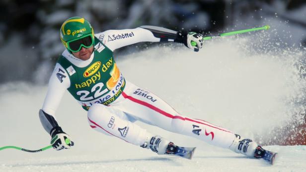 Ein Skirennläufer in voller Montur rast eine schneebedeckte Piste hinunter.