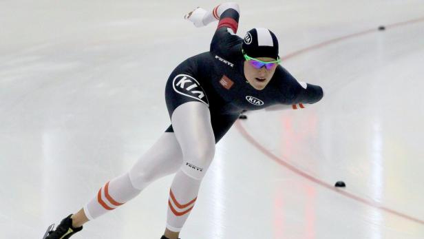 Eine Eisschnellläuferin in Aktion auf einer Eisbahn.