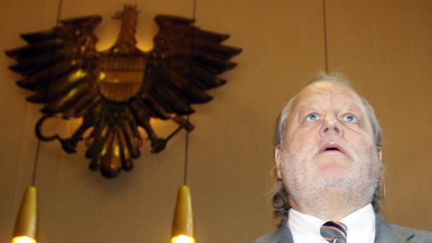 Ein Mann blickt nach oben, im Hintergrund ein österreichischer Bundesadler.