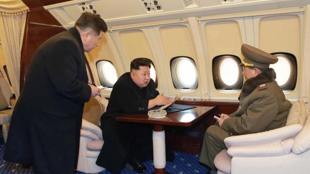 Kim Jong-un bespricht sich mit zwei Offizieren in einem Flugzeug.