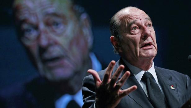 Jacques Chirac hält eine Rede vor einem dunklen Hintergrund.