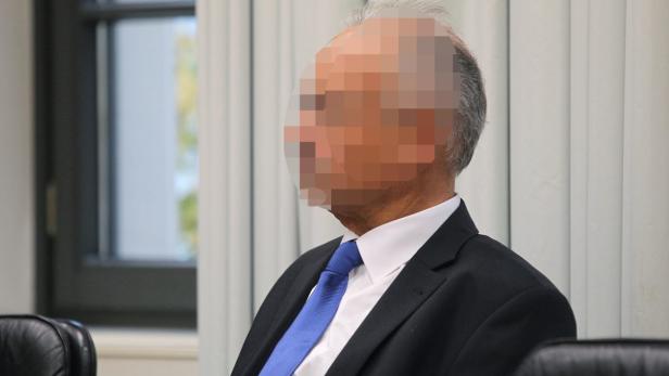 Ein Mann mit Anzug und Krawatte, dessen Gesicht unkenntlich gemacht wurde.