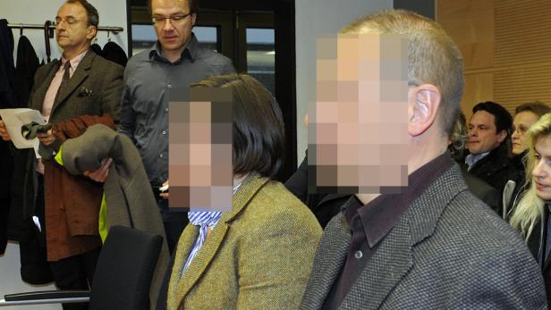 Mehrere Personen sitzen oder stehen in einem Raum, einige Gesichter sind verpixelt.