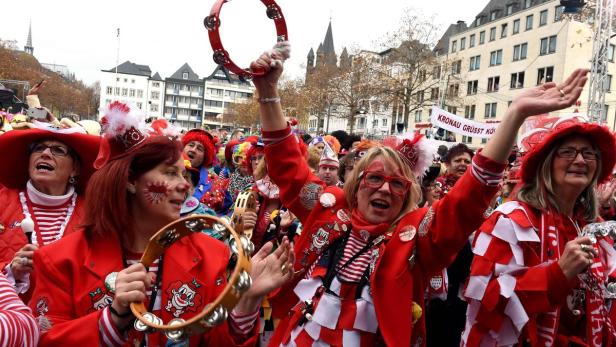 Menschen in rot-weißen Kostümen feiern Karneval in Köln mit Musik und guter Laune.