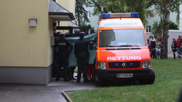Die zwei weiteren Kinder der Familie treffen nach der Bluttat im Wohnhaus in der Koppstraße ein. Einsatzkräfte schirmen sie ab.