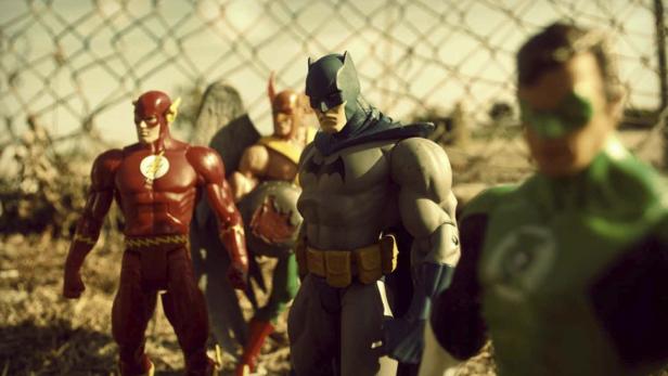 Actionfiguren der Justice League stehen vor einem Zaun.