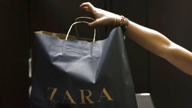 Eine Hand hält eine Einkaufstasche von Zara.