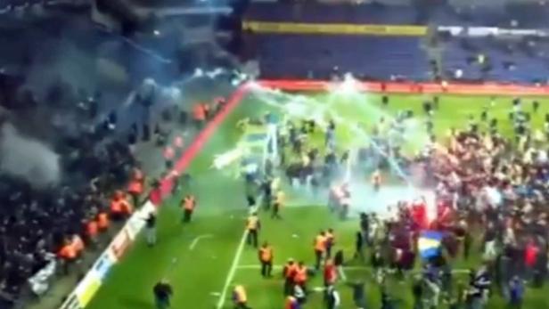 Fans stürmen nach einem Fußballspiel den Rasen.