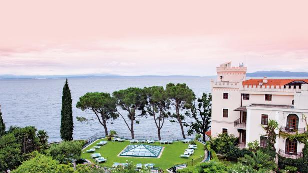 Ein Hotel am Meer mit einem Rasen mit Liegestühlen.