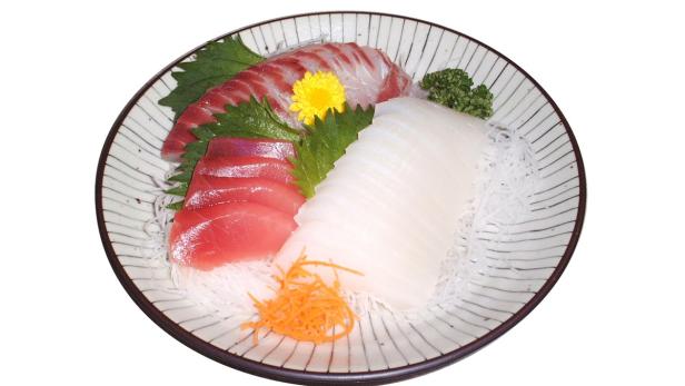 Eine Platte mit verschiedenen Sorten Sashimi, garniert mit Gemüse und einer gelben Blüte.