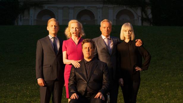 Eine formell gekleidete Gruppe von fünf Personen posiert vor einem Gebäude.
