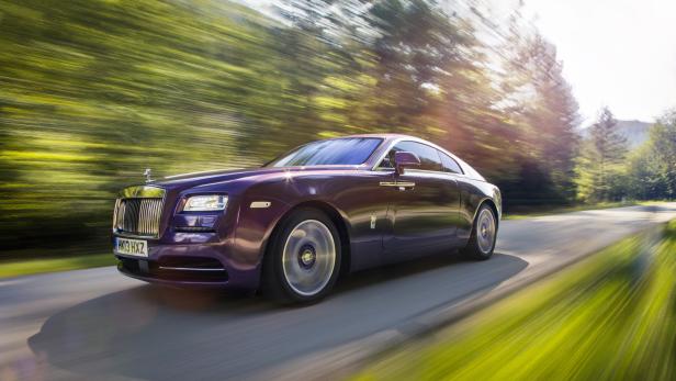 Ein lilafarbener Rolls-Royce fährt auf einer Landstraße.
