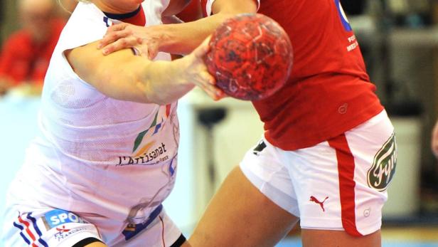 Zwei Handballspielerinnen kämpfen um einen roten Handball.