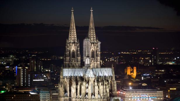 Der Kölner Dom und die Lichter der Stadt bei Nacht.