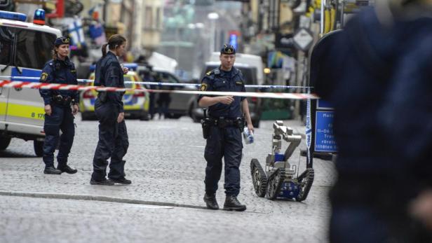 Polizisten und ein Bombenentschärfungsroboter sind auf einer abgesperrten Straße zu sehen.