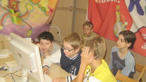 Eine Gruppe von Jungen sitzt vor einem Computer und schaut auf den Bildschirm.