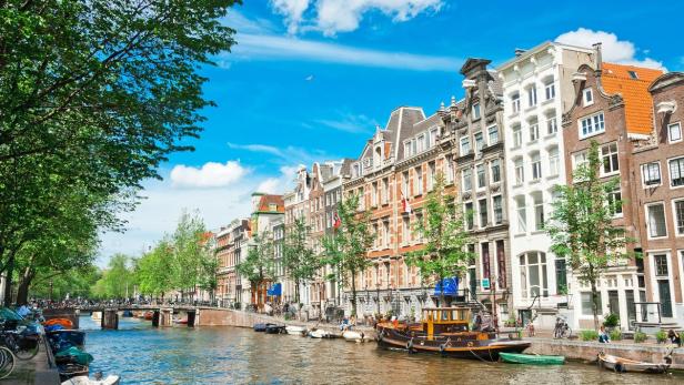 Ein Kanal in Amsterdam mit Booten und historischen Häusern am Ufer.